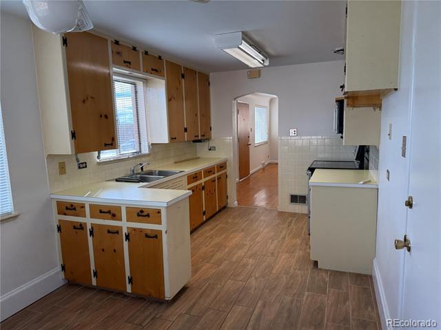 Vacant kitchen with honey-colored cabinets, a small peninsula, and wood-look flooring.