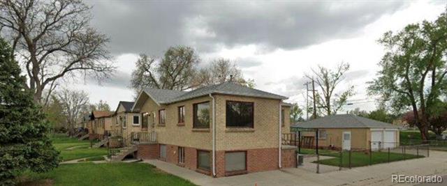Brick residential building with a hipped roof, basement-level windows, and front lawn.