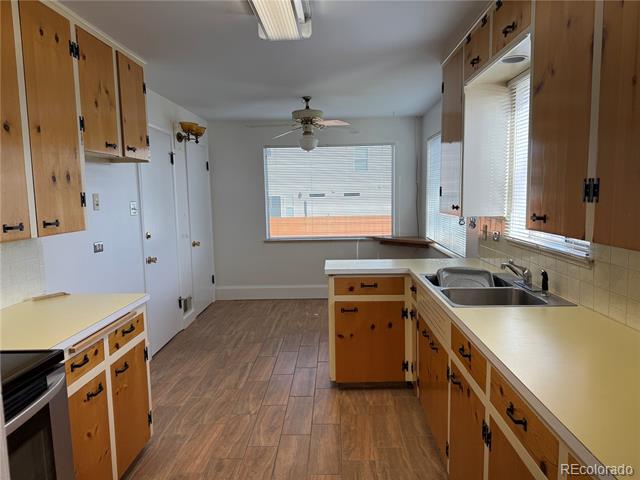 Vacant kitchen with honey-colored cabinets, a double-basin sink, and wood-look flooring.