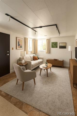 Living room with a cream sofa, armchair, round coffee table, and large curtained windows.