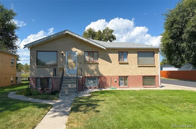 Two-story home with tan siding, a red-brick lower level, front stairs, and a broad lawn.