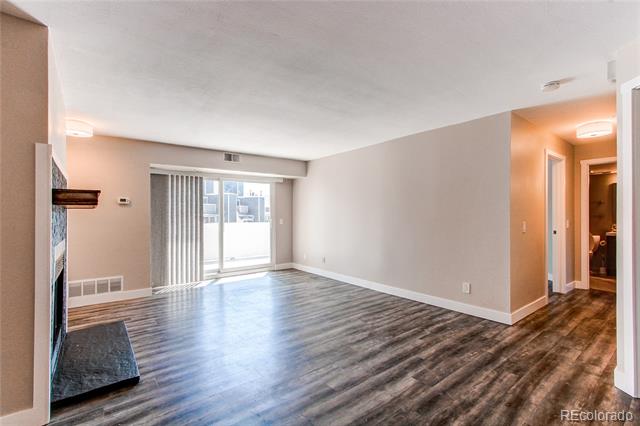Empty condo living room with gray flooring, sliding glass door, and fireplace.
