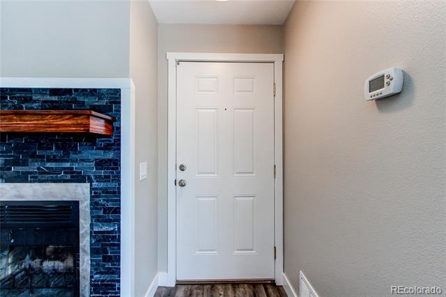 Entryway with a white front door beside a dark stone fireplace.