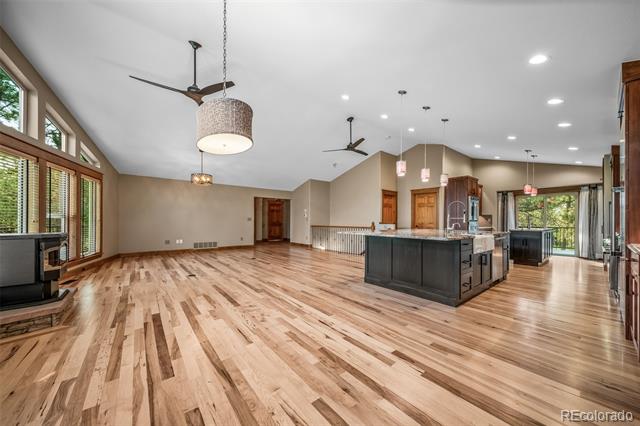Open-plan kitchen and living area with a large island, wood floors, tall windows, and fireplace.