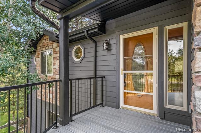 Covered front porch with gray siding, stone accents, and a glass-paneled entry door.
