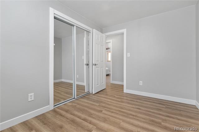 Vacant bedroom with mirrored closet doors and wood-look flooring.