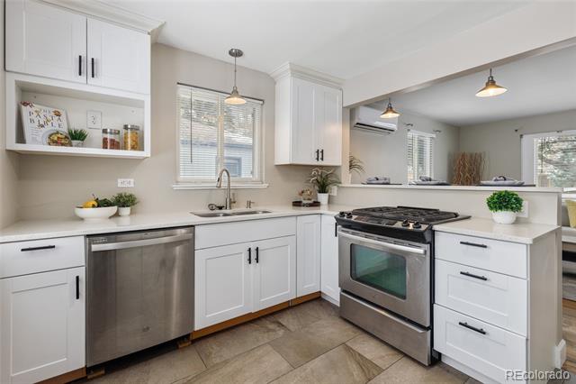 Bright kitchen with white cabinets, stainless steel appliances, and a gas range beside a pass-through.