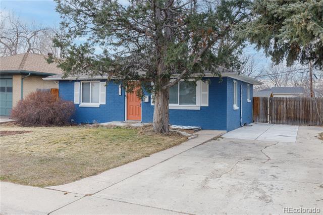 Blue-brick single-story house with an orange front door and wide concrete driveway.