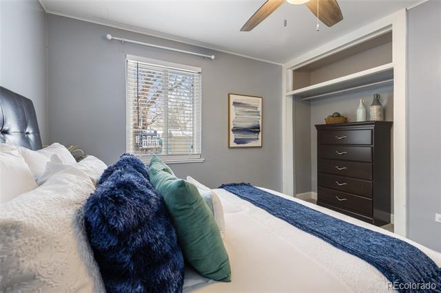 Bedroom with navy and teal pillows, a window with blinds, and a built-in dresser nook.