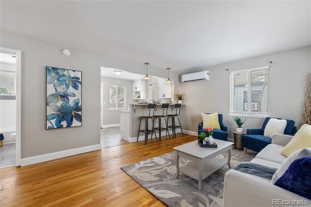 Living room with hardwood floors, blue-and-white seating, and an open kitchen with breakfast bar.