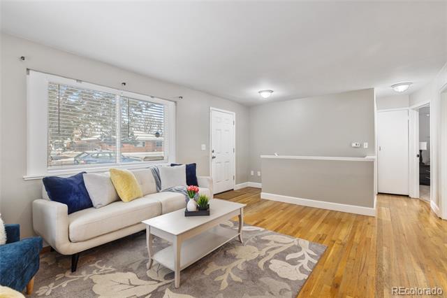 Living room with a light sofa, large window, patterned rug, and hardwood floors.