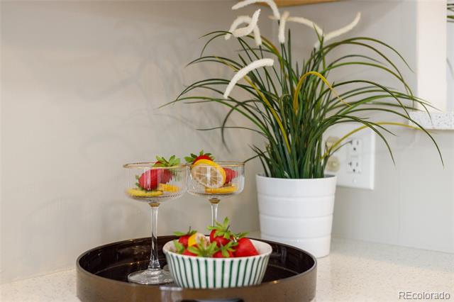 Kitchen countertop with a potted grass plant, fruit bowl, and serving glasses on a tray.