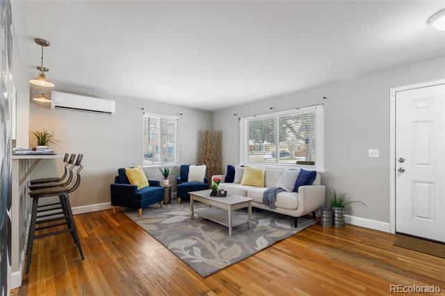 Living room with blue and cream seating, hardwood floors, and large windows.
