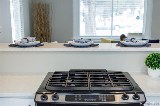 Kitchen with a stainless steel gas cooktop and place settings on the white peninsula.