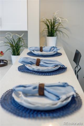 Kitchen counter set with three place settings, blue napkins, and woven placemats.