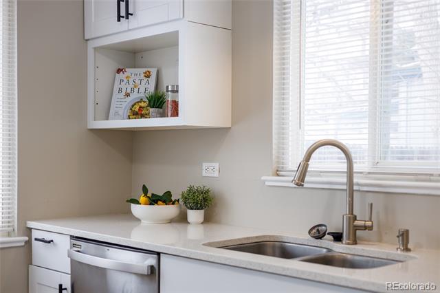 Kitchen with white cabinets, a stainless-steel sink, and a tall faucet beneath a window with blinds.