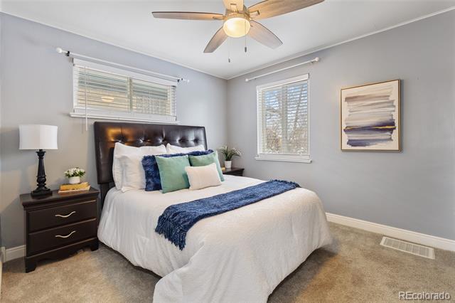 Bedroom with a dark tufted headboard, white bedding, blue accents, and a ceiling fan.