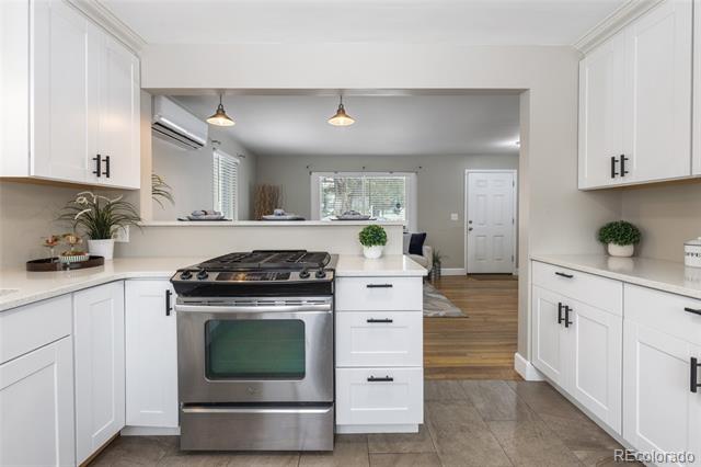 White kitchen with stainless-steel range and a view into the adjoining living area.