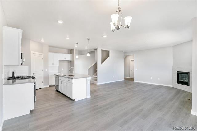 Vacant open-plan kitchen and living area with a white island, gray flooring, and built-in fireplace.