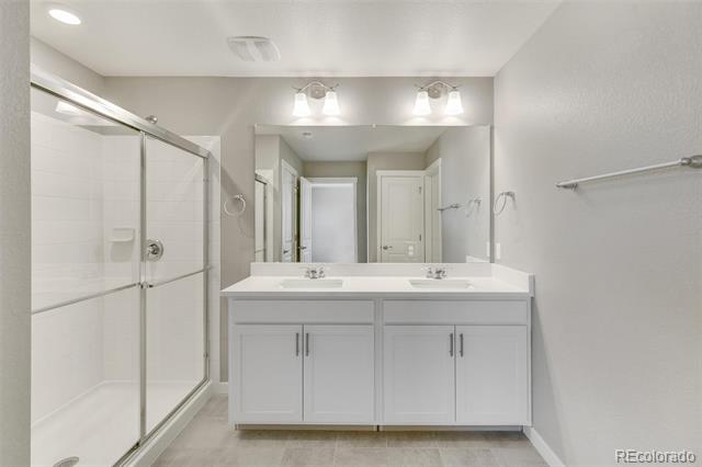 Bathroom with a double-sink vanity, large mirror, and glass-enclosed shower.