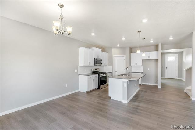 Open-plan kitchen with white cabinets, stainless steel appliances, and a central island.