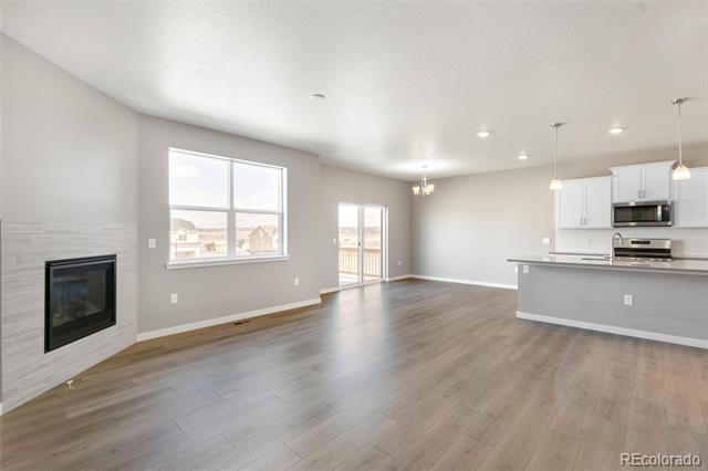 Open living area with a fireplace, kitchen island, and sliding glass doors to a balcony.