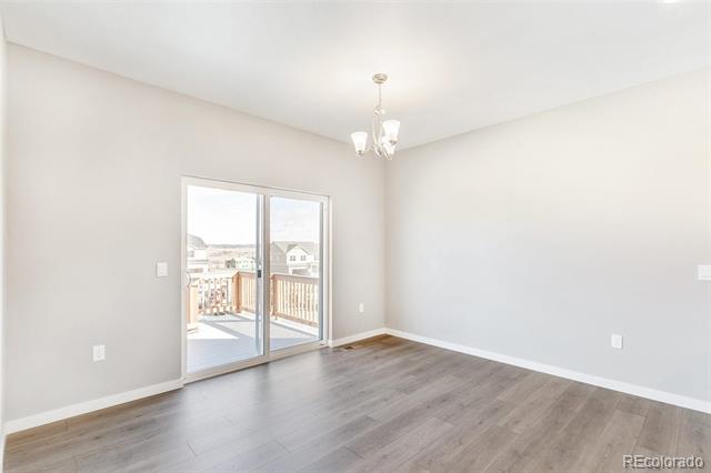 Empty dining area with gray flooring, a chandelier, and sliding glass doors to a deck.