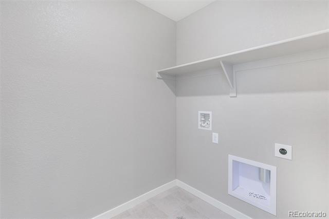 Empty laundry area with a built-in shelf and recessed washer and dryer hookups.