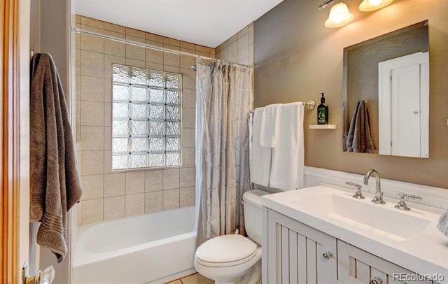 Bathroom with a white tub, glass-block window, and wide vanity with two sinks.