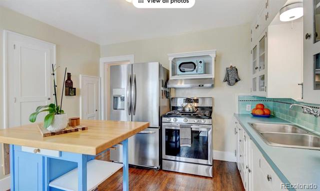 Kitchen with stainless steel appliances, turquoise tile backsplash, and butcher-block island.