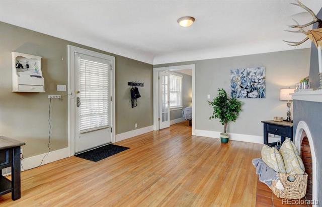 Furnished entry and living area with hardwood floors, a white front door, and a fireplace.