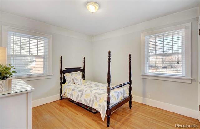 Bedroom with a four-poster bed, shuttered windows, and hardwood flooring.