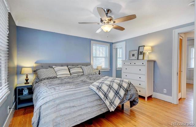 Bedroom with striped bedding, blue-gray walls, a white dresser, and hardwood floors.