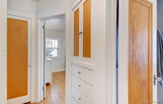 Hallway with white built-in storage and wood cabinet doors, opening onto a room with a window.