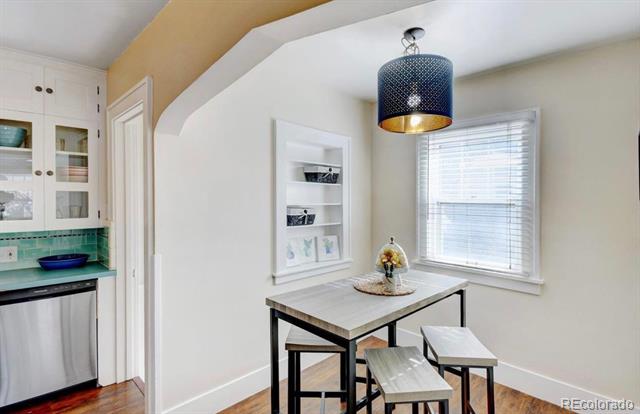 Breakfast nook with a small table and stools beside a turquoise-tiled kitchen counter.