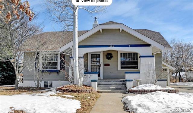 Gray bungalow with blue trim, covered porch, front steps, and snow in the yard.
