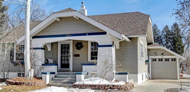 Gray bungalow with a covered porch, blue trim, and attached garage; patches of snow in the yard.
