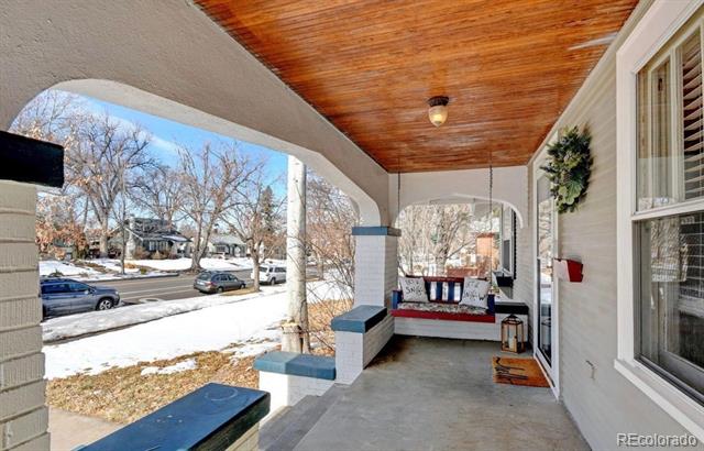 Covered front porch with a wood ceiling, blue-topped brick benches, and a cushioned swing.