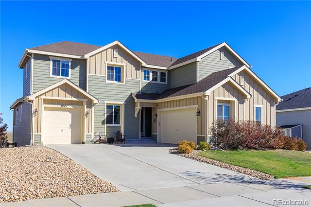 Two-story gray-green and tan home with two garage doors and a wide concrete driveway.