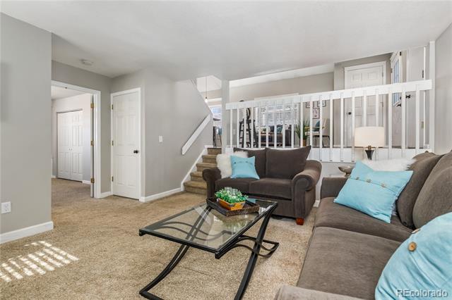 Furnished living room with brown sofas, a glass coffee table, and a white staircase railing.