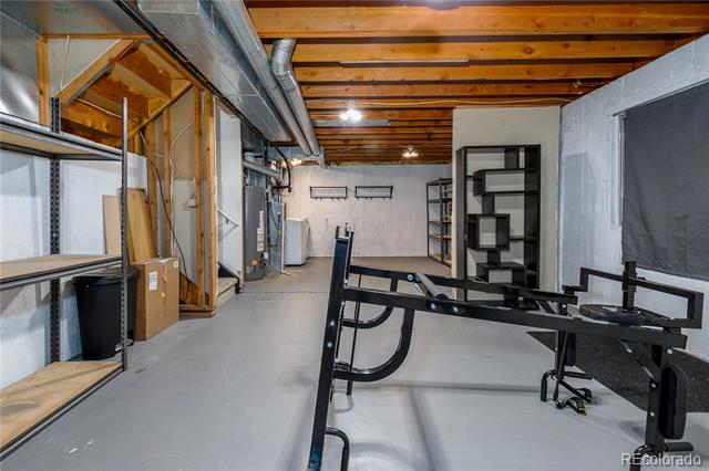 Unfinished basement with exposed ceiling joists, ductwork, and black exercise equipment.