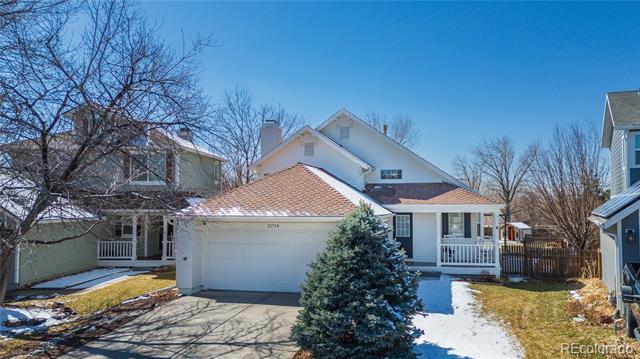 Two-story home with a two-car garage, covered porch, and snow patches across the lawn.