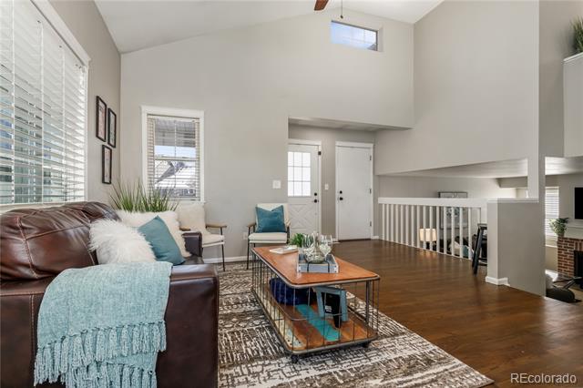 Living room with a leather sofa, blue accents, hardwood floors, and a high ceiling.
