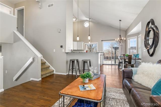 Open-plan living and dining area with a breakfast bar, staircase, and glass patio doors.