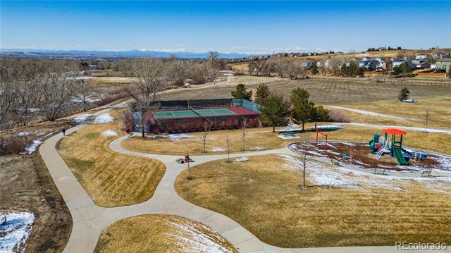 Neighborhood park with winding paths, a fenced tennis court, and a colorful playground.