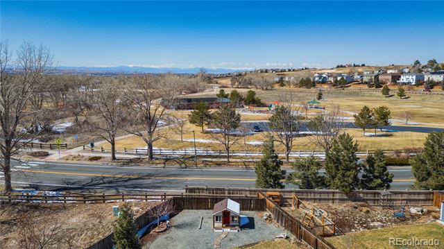Backyard view over a road and open countryside toward distant mountains.