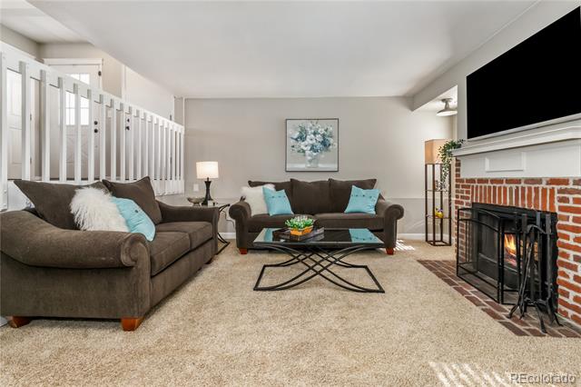 Living room with brown sofas, turquoise pillows, and a brick fireplace.
