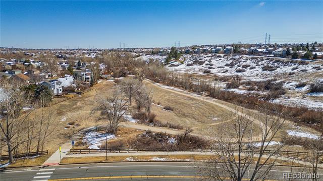 Aerial view of snow-dusted open space, with a road and suburban homes nearby.