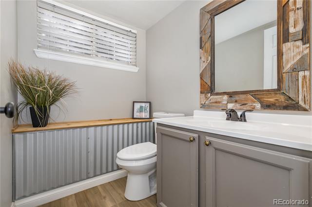 Powder room with gray vanity, rustic wood-framed mirror, and corrugated wainscoting.