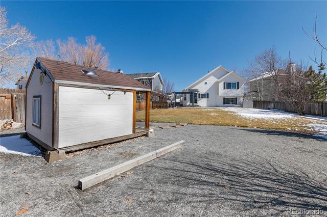 Detached garage beside the home, with a gravel driveway and snow-dusted yard.